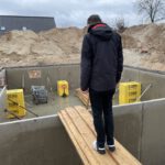 Stillstand am Rohbau, Mann schaut in einen Keller-Rohbau